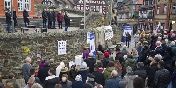 Thomas Meinhardt vom Bündnis „Idstein ist bunt“ spricht von der Rathausbrücke zu den weit mehr als 200 Menschen, die zur Mahnwache für die Opfer des Terroranschlags in Hanau gekommen sind. Foto: Mallmann/AMP